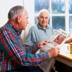 Two senior men enjoying coffee and a newspaper.